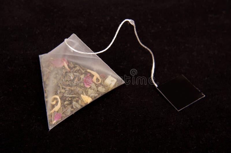 Teabag in the pyramid shape on the dark background. Teabag in the pyramid shape on the dark background