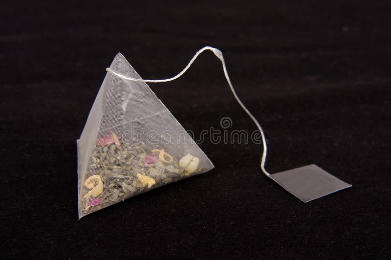 Teabag in the pyramid shape on the dark background. Teabag in the pyramid shape on the dark background