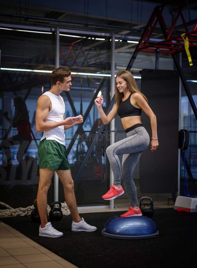 Oszałamiająco dziewczyna pracująca z stepper w gym tle out Kobiety szkolenie z młodym trenerem w sprawność fizyczna klubie zdjęcia stock