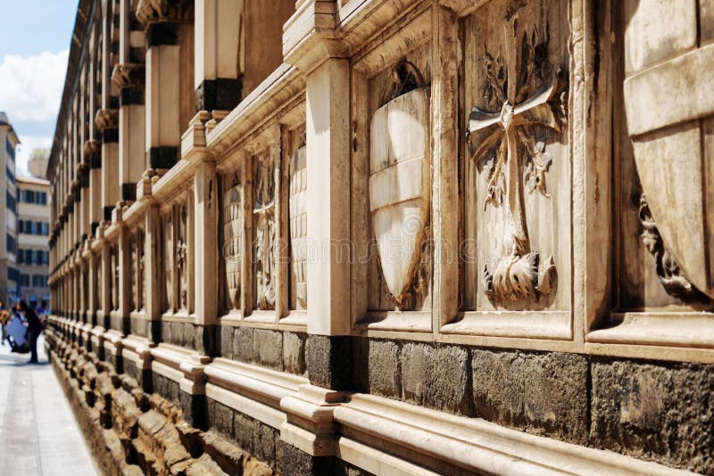 Closeup view of shields and crosses on sepulchral niches of old cemetery in the Church of Santa Maria Novella in Florence, Tuscany, Italy. View from the Via degli Avelli street. Closeup view of shields and crosses on sepulchral niches of old cemetery in the Church of Santa Maria Novella in Florence, Tuscany, Italy. View from the Via degli Avelli street.