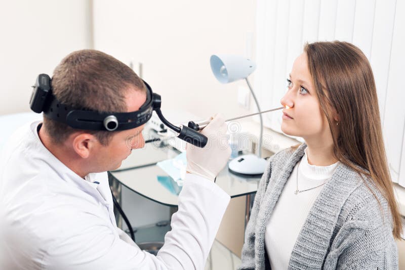 Otolaryngologist. Very attentive medical worker looking at nose of his visitor royalty free stock image Otolaryngologist. Very attentive medical worker looking at nose of his visitor royalty free stock image