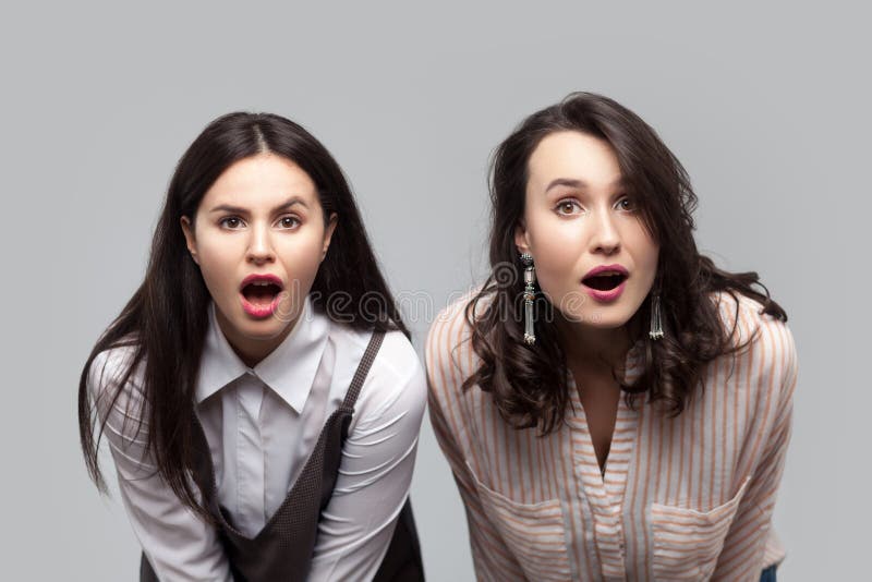 Otrolig nyheterna Closeupstående av chockade härliga brunettflickor i tillfällig stil som tillsammans står och ser kameran arkivfoto Otrolig nyheterna Closeupstående av chockade härliga brunettflickor i tillfällig stil som tillsammans står och ser kameran arkivfoto