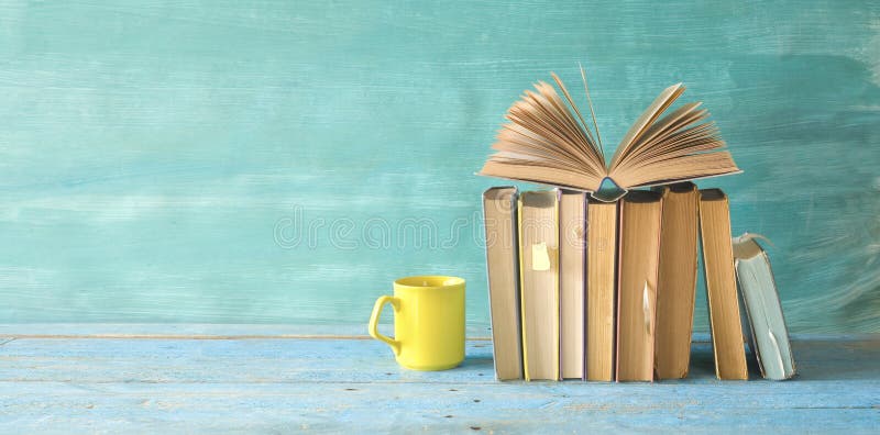 Otwiera książkę na rzędzie stare książki i filiżanka kawy Czytający, uczący się, edukacja, literatura tematy