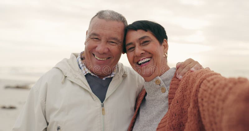 Oud echtpaar hug en selfie op het strand geluk en pensioen samen reizen en geheugen buiten. portret blij