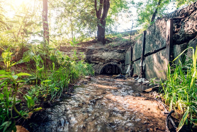 Oude concrete drainagepijpen met stromende afvalwater, riolerings of rioleringstunnelbuis met waterstroom royalty-vrije stock afbeelding Oude concrete drainagepijpen met stromende afvalwater, riolerings of rioleringstunnelbuis met waterstroom royalty-vrije stock afbeelding