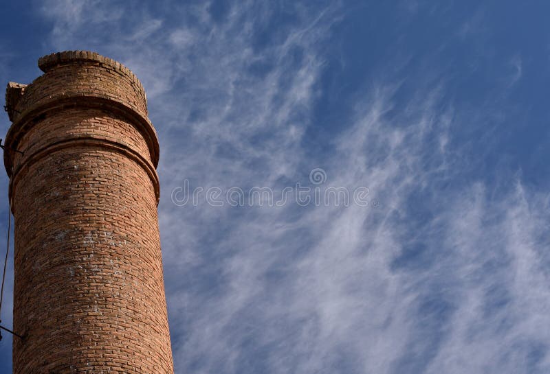Oude fabriekskoorts in een blauwe lucht met wolken royalty-vrije stock afbeelding Oude fabriekskoorts in een blauwe lucht met wolken royalty-vrije stock afbeelding