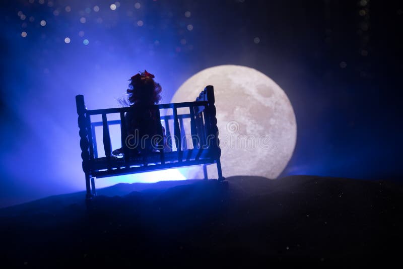 Old creepy eerie wooden baby crib standing on hill with a big full moon. Horror concept. Scary baby and bed silhouette in dark. Creative artwork decoration. Selective focus. Old creepy eerie wooden baby crib standing on hill with a big full moon. Horror concept. Scary baby and bed silhouette in dark. Creative artwork decoration. Selective focus
