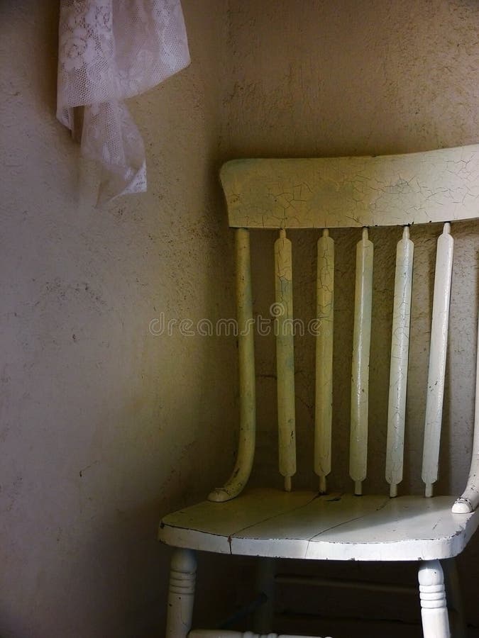 Old wooden chair in the corner of a bleak looking room. Old wooden chair in the corner of a bleak looking room