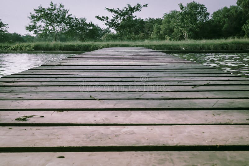 Oude Houten Voetbrug met leuningen over het overzees het bewegen zich op conceptenidee stock foto Oude Houten Voetbrug met leuningen over het overzees het bewegen zich op conceptenidee stock foto