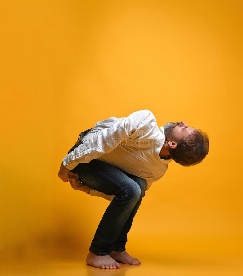 Oude mens het praktizeren yoga die uitrekkende oefeningen doen tegen gele achtergrond stock foto's Oude mens het praktizeren yoga die uitrekkende oefeningen doen tegen gele achtergrond stock foto's