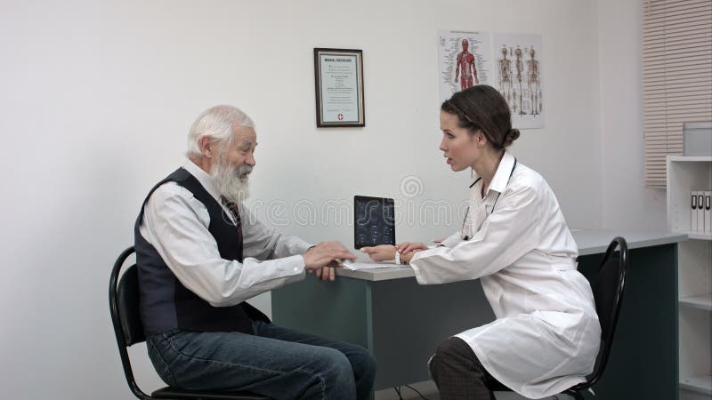 Oude patiënt talkint aan jonge vrouwelijke arts