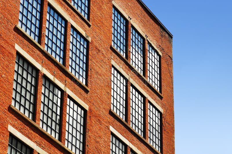 Old red brick building or factory with many small windows with top corner close to tumbling down because of cracks. Old red brick building or factory with many small windows with top corner close to tumbling down because of cracks.