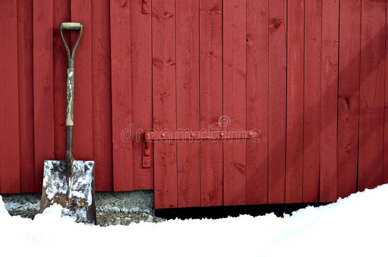 Oude sneeuw die showel op rode schuurmuur rusten in de sneeuwwinter stock afbeeldingen Oude sneeuw die showel op rode schuurmuur rusten in de sneeuwwinter stock afbeeldingen