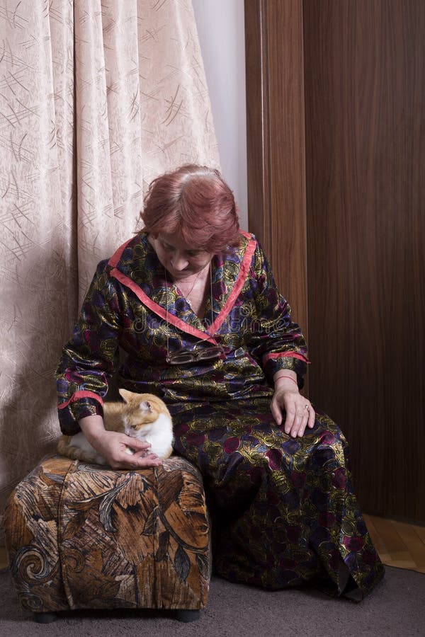 Oude vrouw met een kat in haar huis stock foto Oude vrouw met een kat in haar huis stock foto