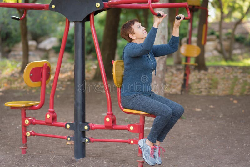 Oudere mens die op de sporten openbaar materiaal in de openluchtgymnastiek uitwerkt stock foto's Oudere mens die op de sporten openbaar materiaal in de openluchtgymnastiek uitwerkt stock foto's