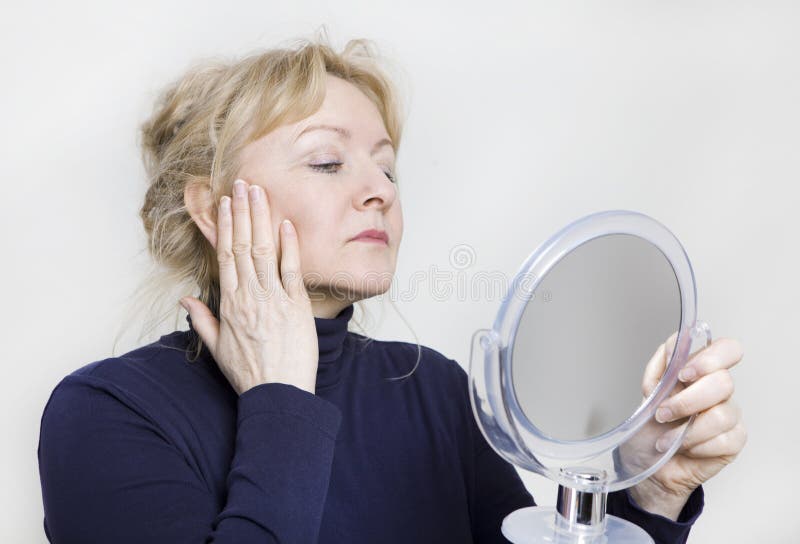 Oudere vrouw die in spiegel kijken stock foto Oudere vrouw die in spiegel kijken stock foto