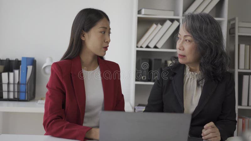 Oudere zakenvrouw en jonge aziatische accountant die het hebben over bedrijfsfinanciën en boekhoudkundige activiteiten op kantoor