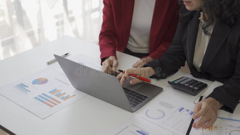 Oudere zakenvrouw en jonge aziatische accountant die het hebben over bedrijfsfinanciën en boekhoudkundige activiteiten op kantoor