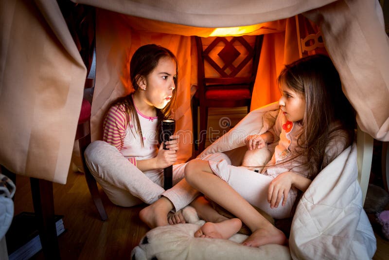 Portrait of elder sister telling scary story to younger one at late night in bedroom. Portrait of elder sister telling scary story to younger one at late night in bedroom