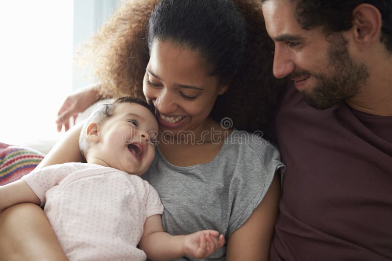 Ouders die op Sofa Cuddling Baby Daughter At-Huis zitten