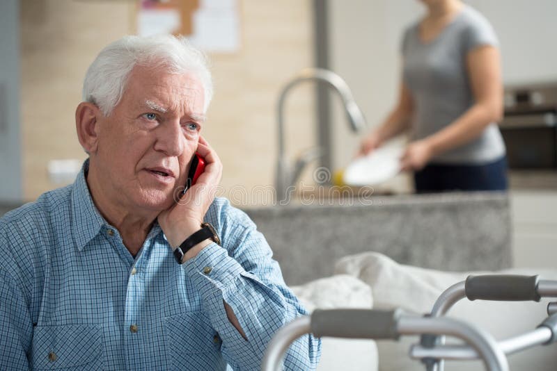 Senior talking on the phone and granddaughter washing dishes. Senior talking on the phone and granddaughter washing dishes