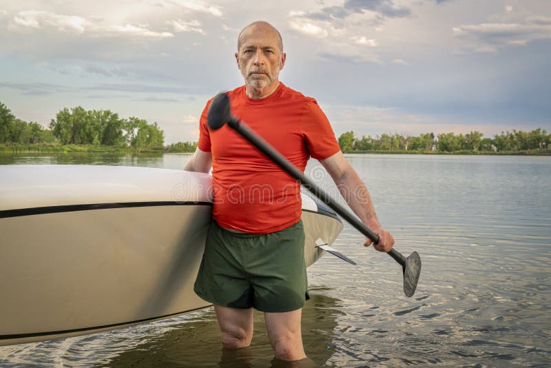 Oudste paddler met zijn tribune omhoog paddleboard royalty-vrije stock fotografie Oudste paddler met zijn tribune omhoog paddleboard royalty-vrije stock fotografie