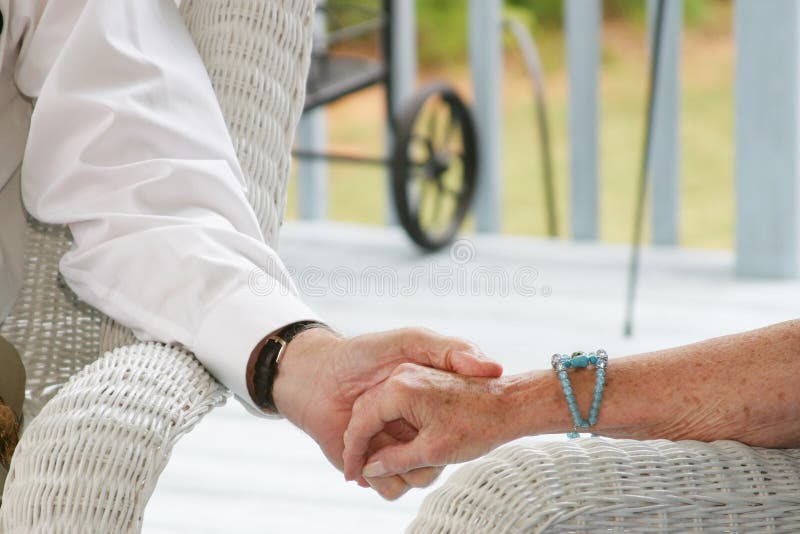 Seniors holding hands outside sitting on porch. Seniors holding hands outside sitting on porch