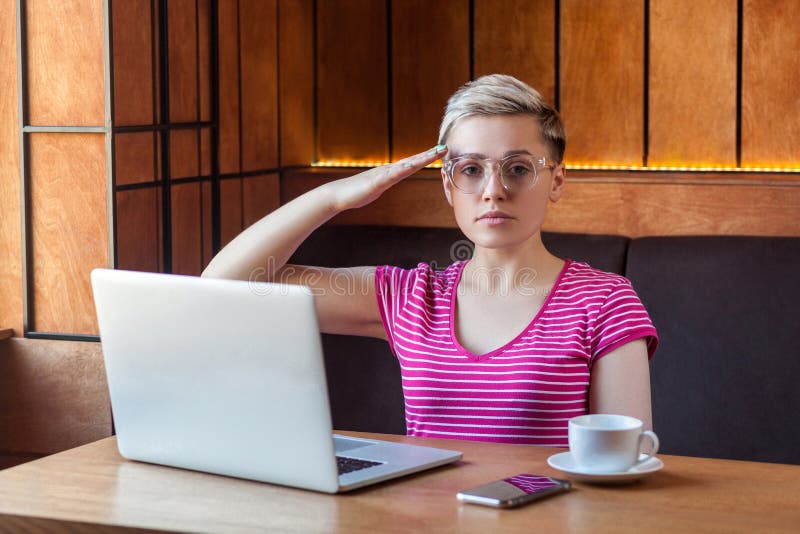 Oui, monsieur! Portrait d'une jeune fille fidèle indépendante aux cheveux courts, en t-shirt rose, les lunettes sont assises au image stock