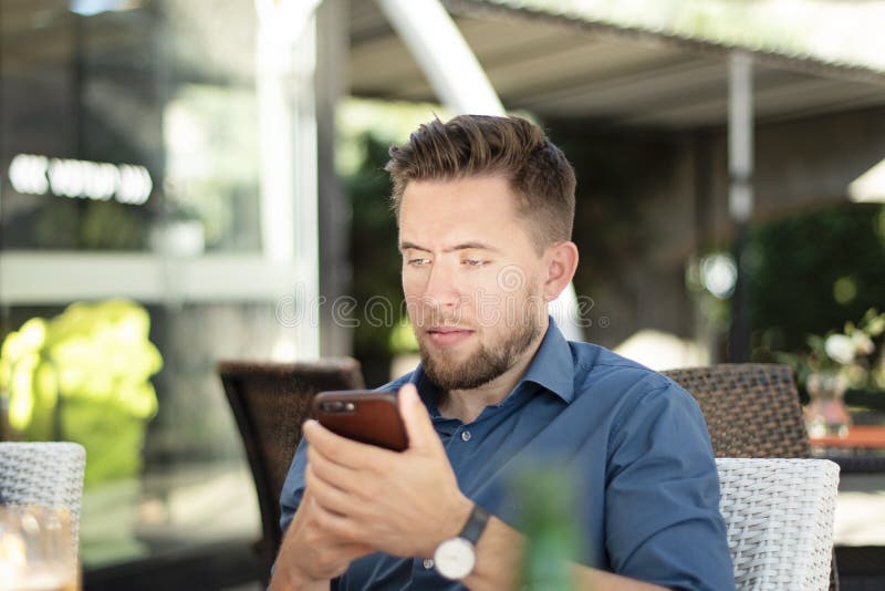 Oungs-gut aussehender Mann, der seinen Handy betrachtet lizenzfreies stockfoto Oungs-gut aussehender Mann, der seinen Handy betrachtet lizenzfreies stockfoto