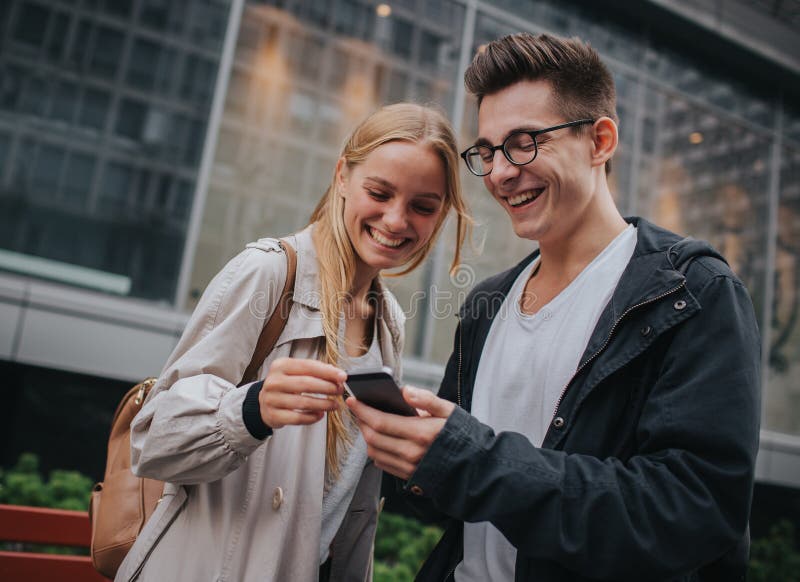 Ouple или смеяться над друзей смешной и иметь потеху с умным телефоном в большой улице города стоковая фотография rf Ouple или смеяться над друзей смешной и иметь потеху с умным телефоном в большой улице города стоковая фотография rf