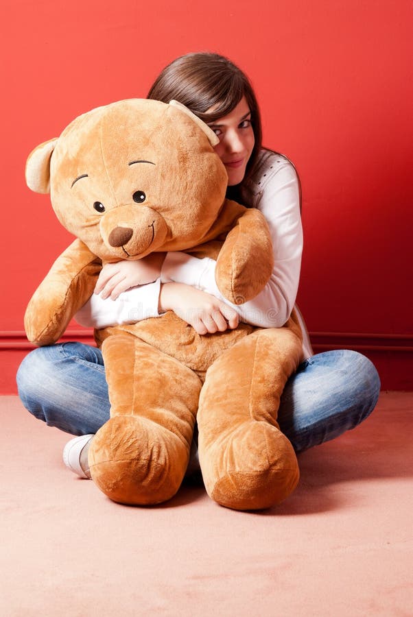 Ours de nounours d'embrassement de jeune femme se reposant sur l'étage photos stock Ours de nounours d'embrassement de jeune femme se reposant sur l'étage photos stock
