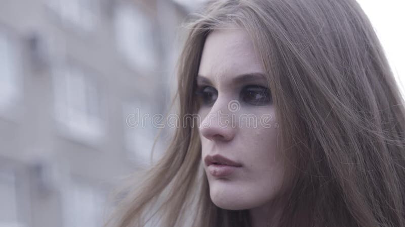 Outdoor beauty portrait of young brown haired girl looking aside over blurred city line background. Action. Close up for