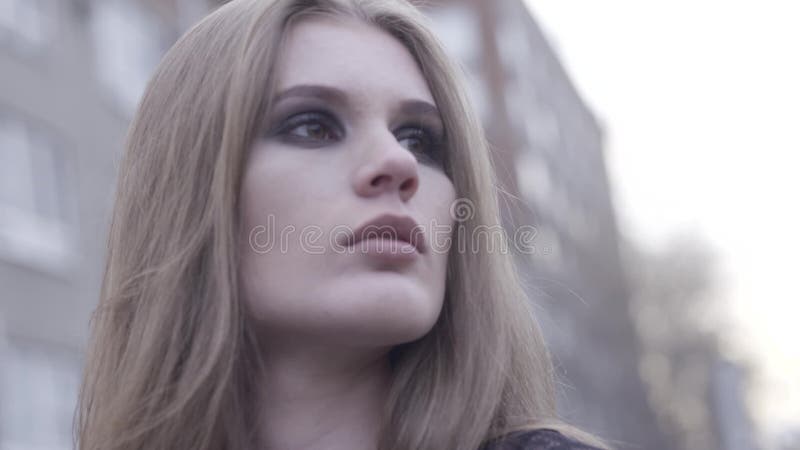 Outdoor beauty portrait of young brown haired girl looking aside over blurred city line background. Action. Close up for