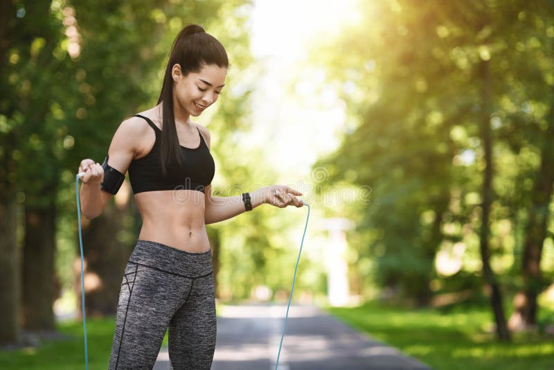 Outdoor Fitness. Sporty Asian Girl Using Skipping Rope For Training In Park, Free Space