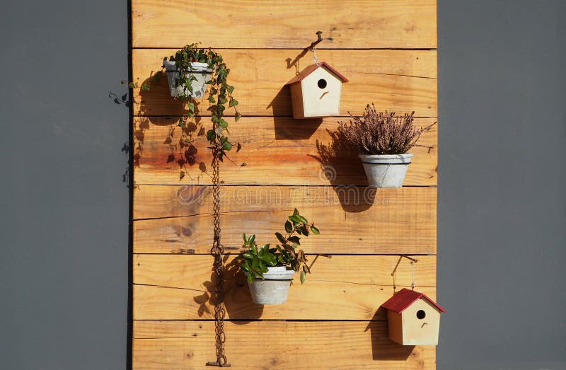 Outdoor garden wall decorations. Flower pots and bird houses hang on raw wooden panels.