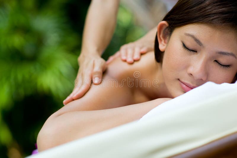 Eine junge Frau, die die massage draußen im tropischen Garten.