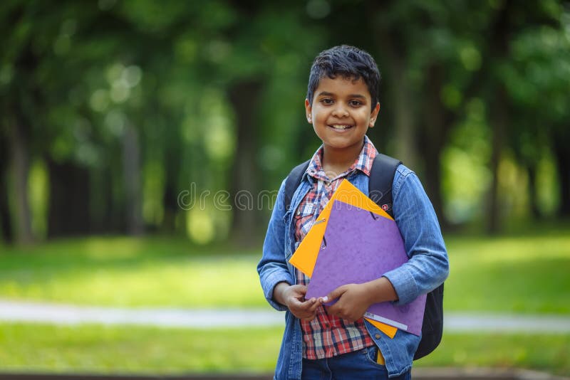 Outdoor portrait afro american happy school boy with books and backpack. Young student beginning of class after vacation