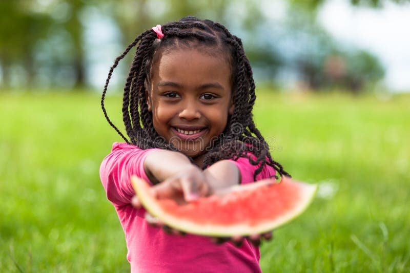 Outdoor portrait of a cute young black little girl eating watermelon - African people royalty free stock image Outdoor portrait of a cute young black little girl eating watermelon - African people royalty free stock image