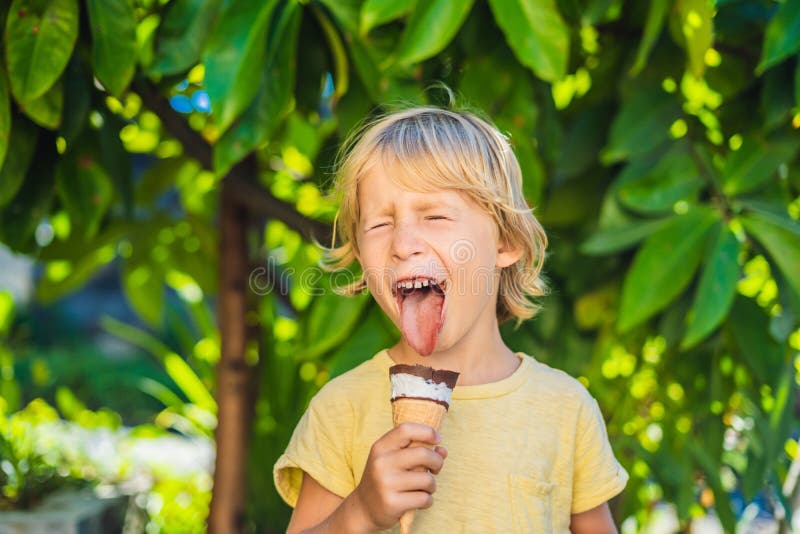 Outdoor portrait of happy boy with ice cream in waffles cone. Cute child holding ice-cream and making gladness face stock photos Outdoor portrait of happy boy with ice cream in waffles cone. Cute child holding ice-cream and making gladness face stock photos
