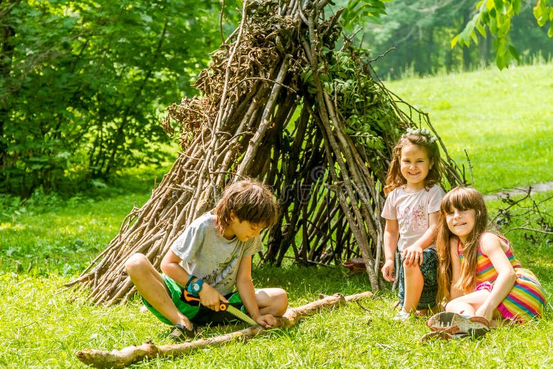 Outdoor portrait of three happy kids - boy and girls - playing n