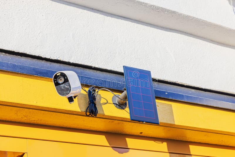 Outdoor security camera mounted on yellow wall with solar panel, capturing sunlight for eco-friendly surveillance. Sweden. Capturing sunlight stock images, royalty-free photos and pictures