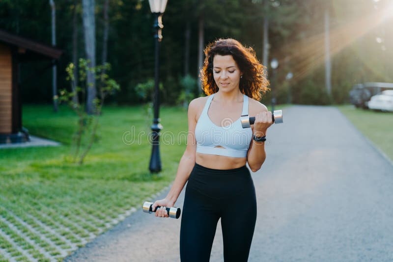 Slim motivated brunette woman dressed in cropped top and leggings