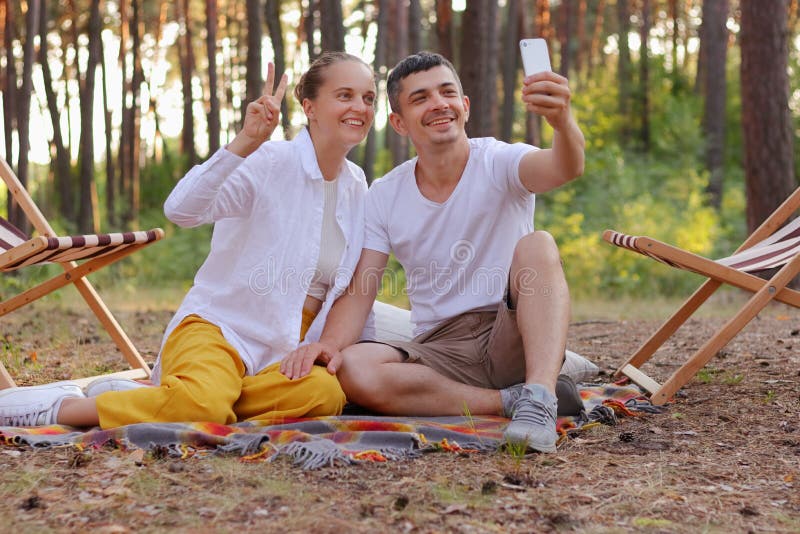 Outdoor Shot of Smiling Couple Sitting in the Forest and Broadcast