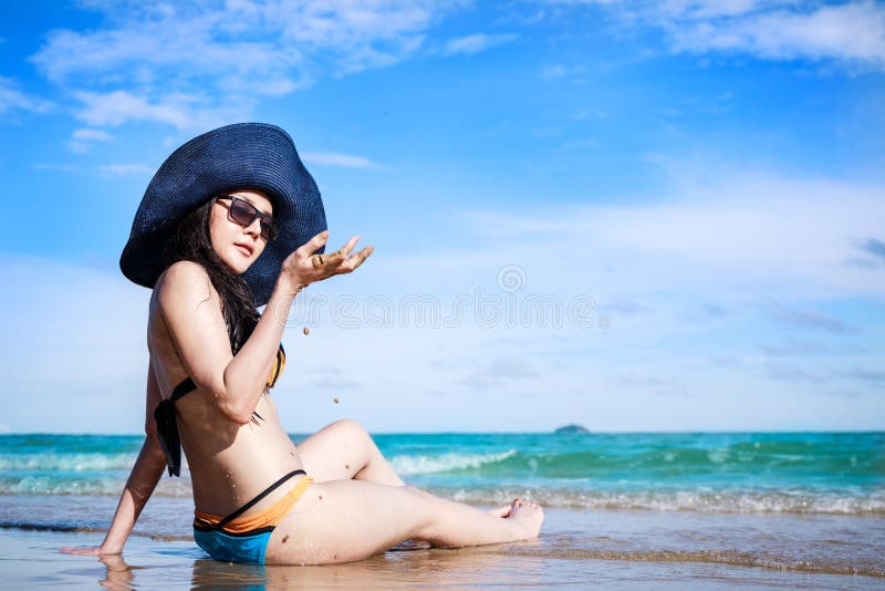 Outdoor summer portrait of Asian beautiful girl in a sexy bikini sitting on the beach in summer. teenage girls. sexy body. concept