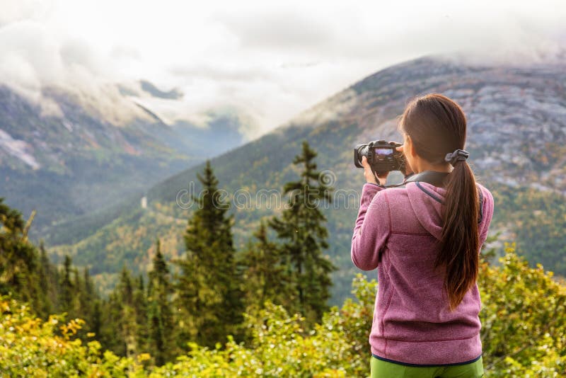 Outdoor travel lifestyle woman photographer shooting video camera at Alaska background. USA vacation holiday in Autumn