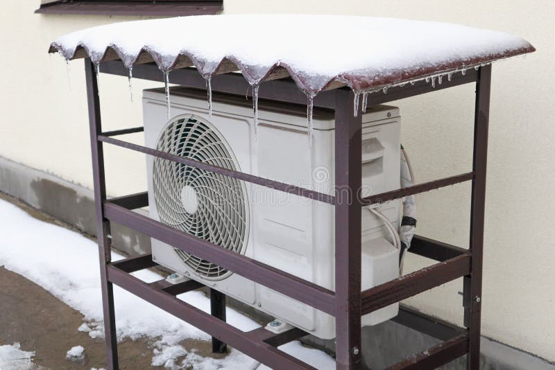 The outdoor unit of the air conditioner (air-to-air heat pump) in the snow during winter