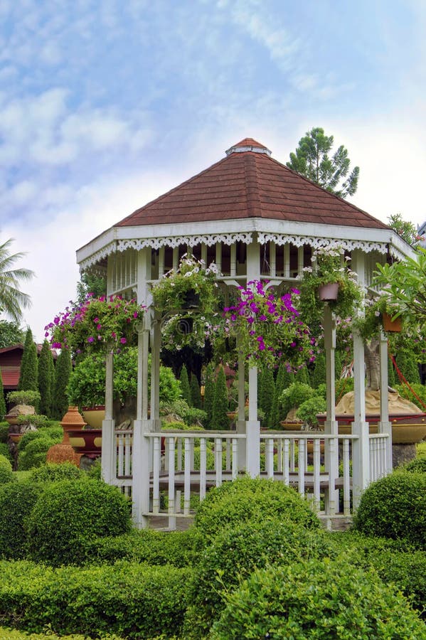 Outdoor wooden gazebo with flowers in a beautiful garden