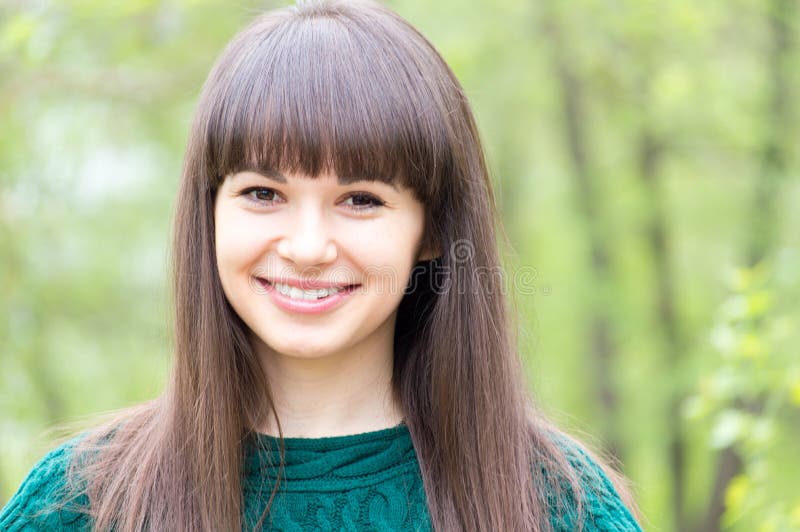 Outdoors closeup portrait of young beautiful woman brunette girl happy smiling & looking at camera on summer green background