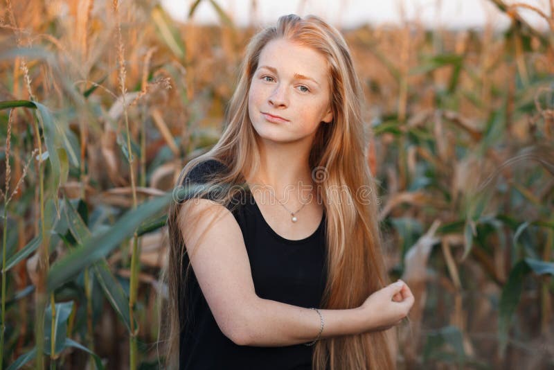 Outdoors lifestyle portrait of young adorable fresh looking redhead woman with freckles gorgeous extra long hair corn field sunny