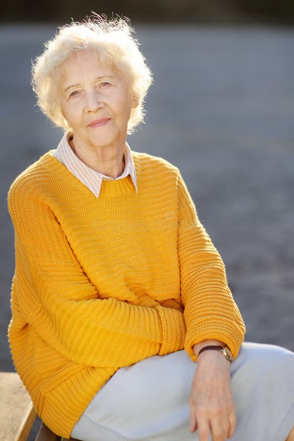 Outdoors portrait of beautiful smiling senior woman with curly white hair. Elderly lady walking in autumn park royalty free stock image Outdoors portrait of beautiful smiling senior woman with curly white hair. Elderly lady walking in autumn park royalty free stock image